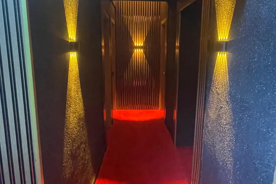 Duvar lambalarıyla aydınlanan, kırmızı halılı koridor